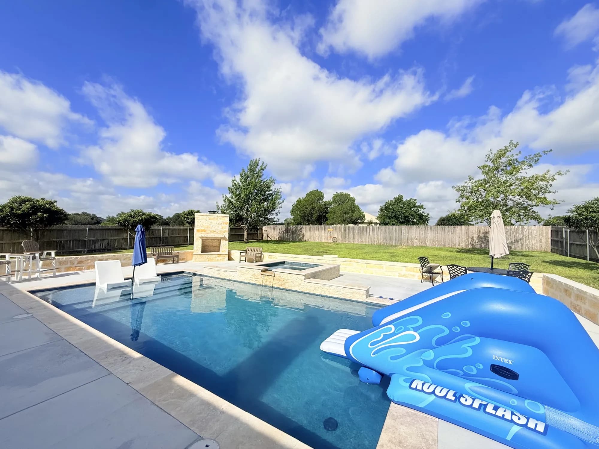 Geometric gunite pool with tanning ledge loungers and raised spa spillover