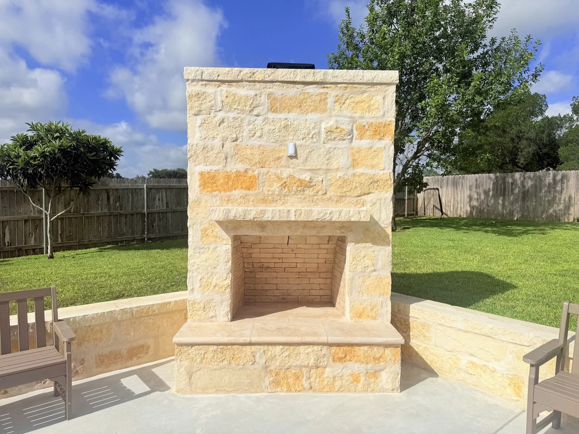 Limestone outdoor wood-burning fireplace with seating walls