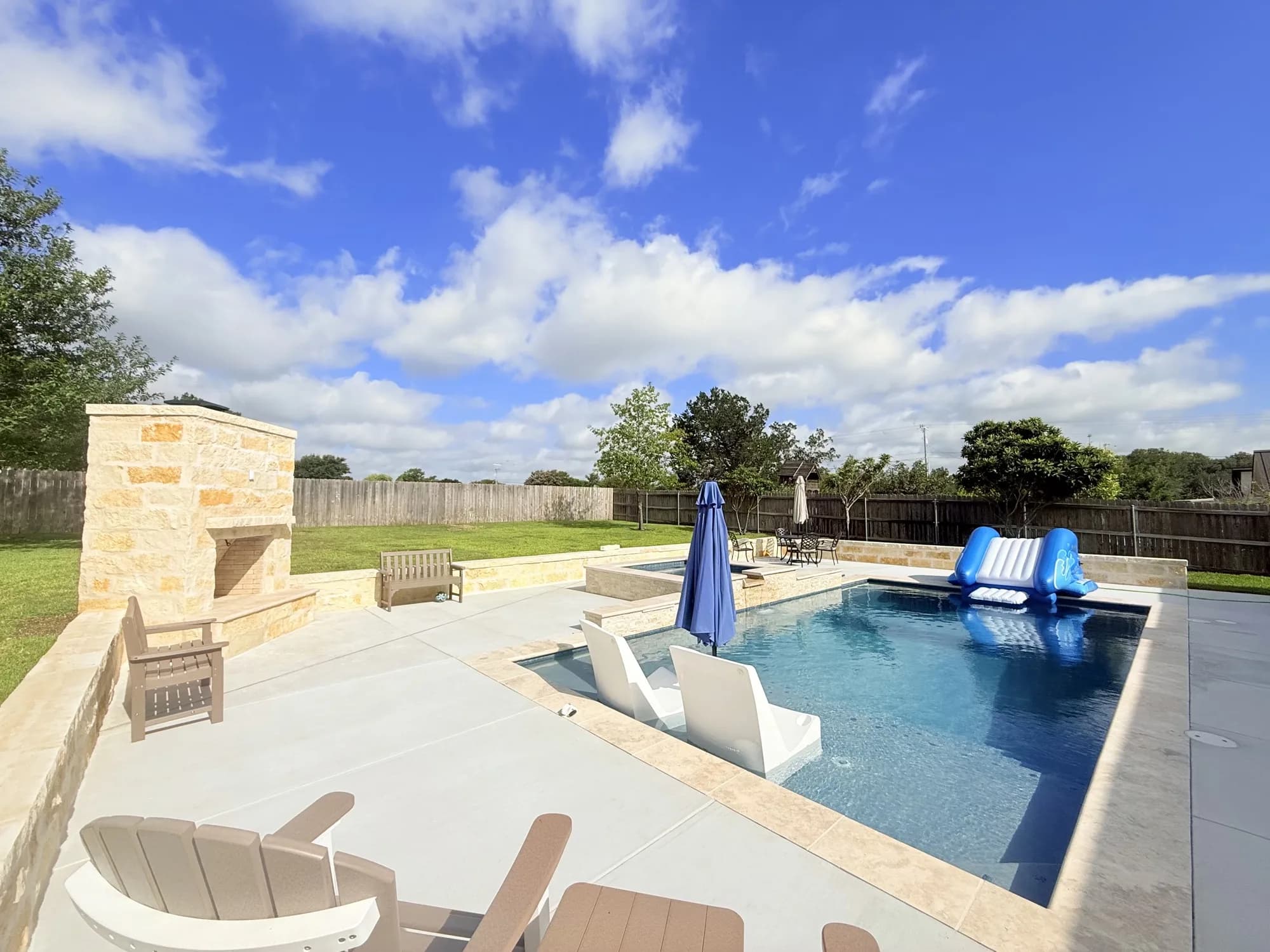 Finished geometric gunite pool with raised spa, limestone seating walls, and outdoor fireplace